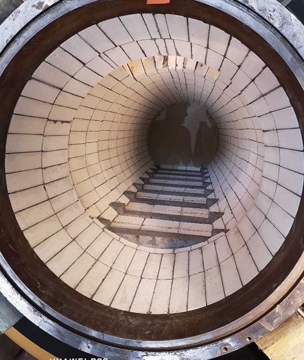 Revêtement réfractaire d'un four : tunnel de briques blanches. Vue plongeante dans le tunnel d'un four industriel, révélant un revêtement en briques réfractaires blanches formant des marches successives.